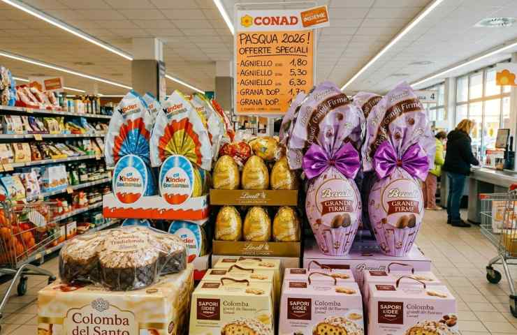 Corsia supermercato Conad con esposizione uova di Pasqua Kinder, Lindt e colombe in offerta per Pasqua 2026.