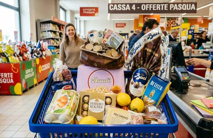 Cesto della spesa pieno di uova di Pasqua e dolci con borsellino pieno di euro in contanti al supermercato.