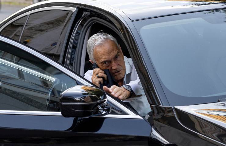 Gabriele Gravina seduto in un'auto nera con lo sportello aperto mentre parla al telefonino.