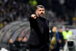Rino Gattuso in giacca nera mentre indica qualcosa in campo con espressione apprensiva.